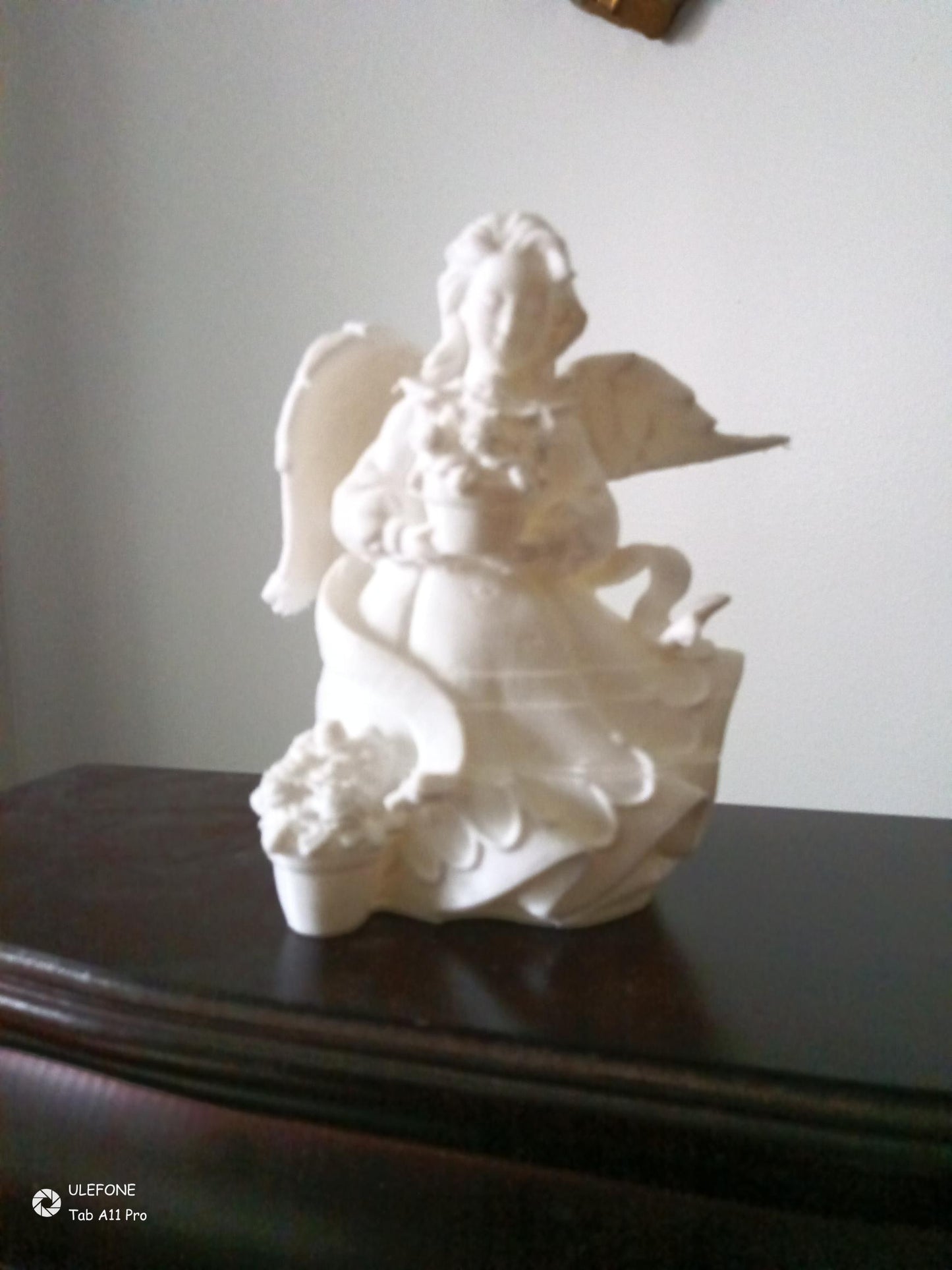 White angel figurine on a dark surface with a plain background