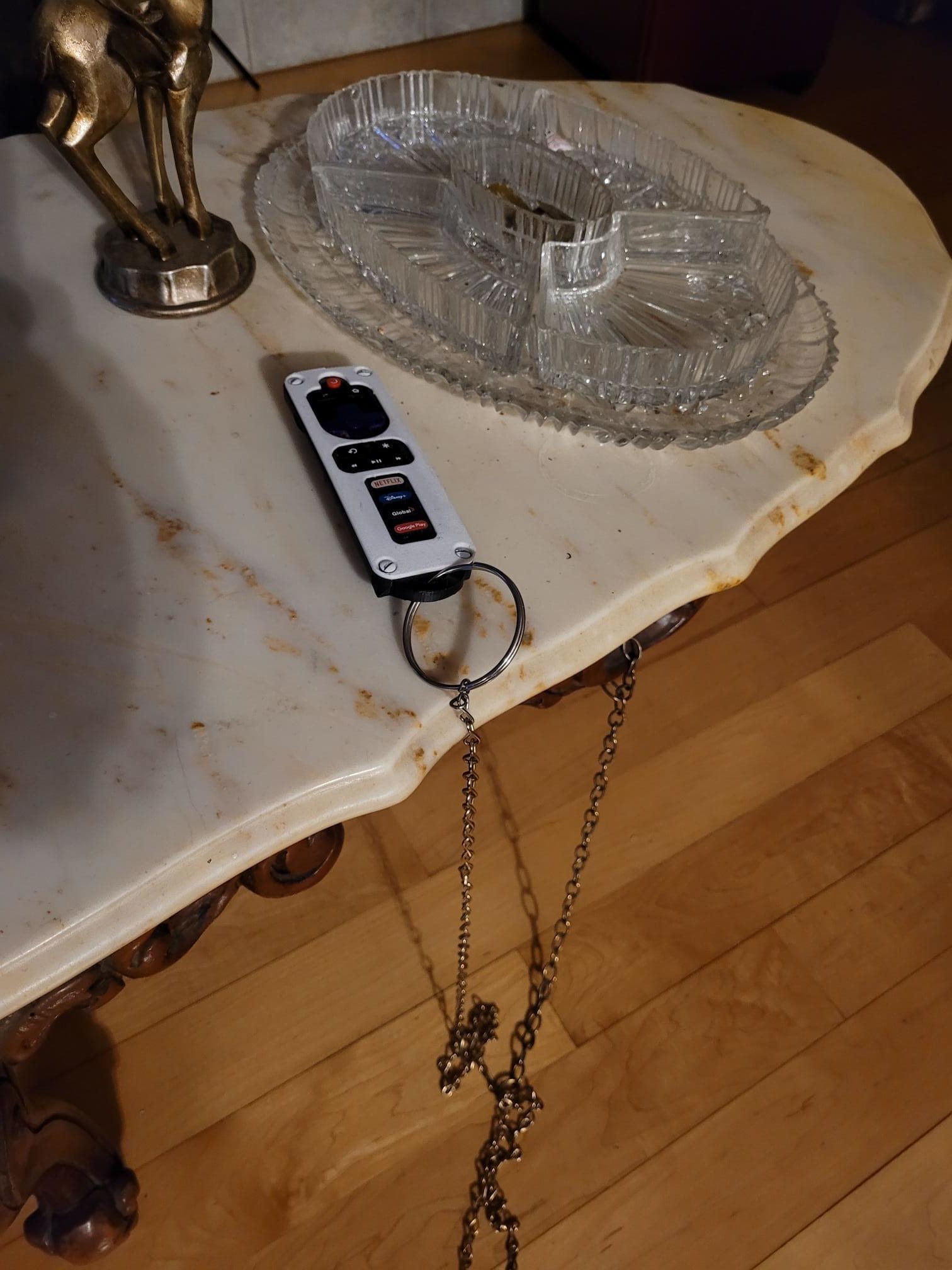 A Roku remote control case attached to a glass dish on a wooden table.